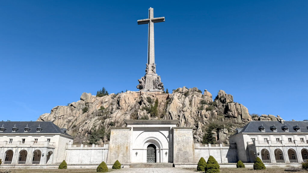 Tall stone cross monument atop a rocky hill.
