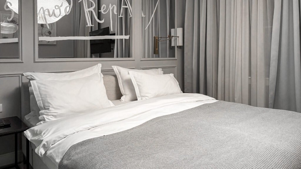Apartment Zagreb | Krista the Explorer King-size bed with white pillows and a textured gray bedspread in a modern hotel room.