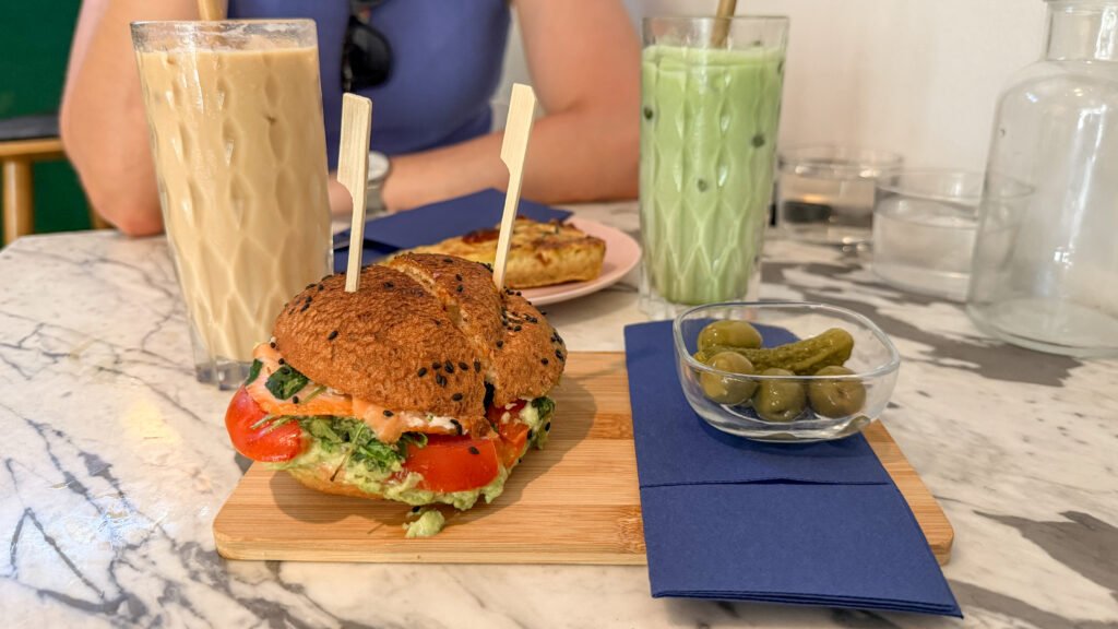 Salmon breakfast bun next to lattes and a quiche.