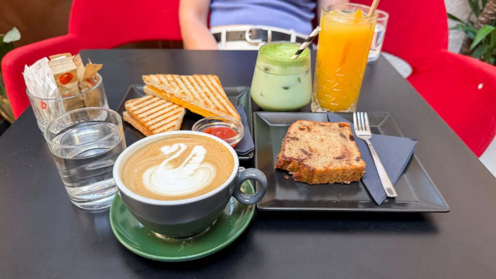 Black table with spread of pastries and iced drinks.