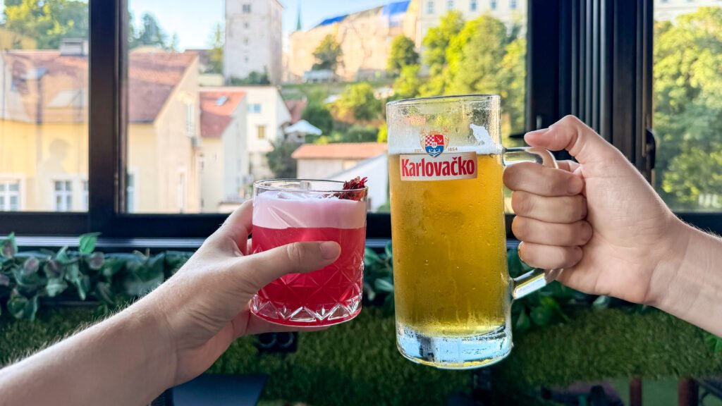 Two hands clinking glasses inside rooftop bar.