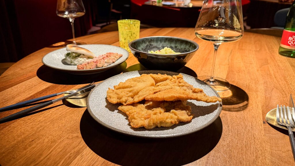 Plate of pork schnitzel with potato salad in black bowl.