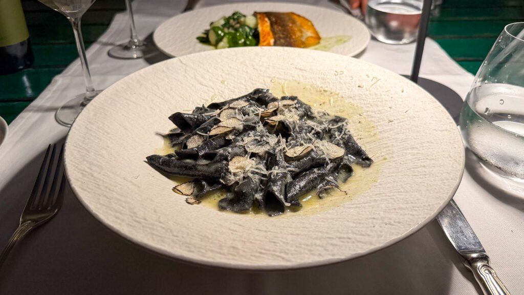 Squid ink pasta with cream sauce and shaved cheese topped with fresh truffle.