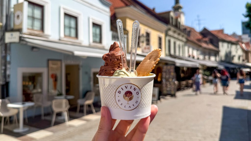 Divino Gelato Zagreb | Krista the Explorer Hand holding a cup of chocolate and vanilla gelato with a wafer.
