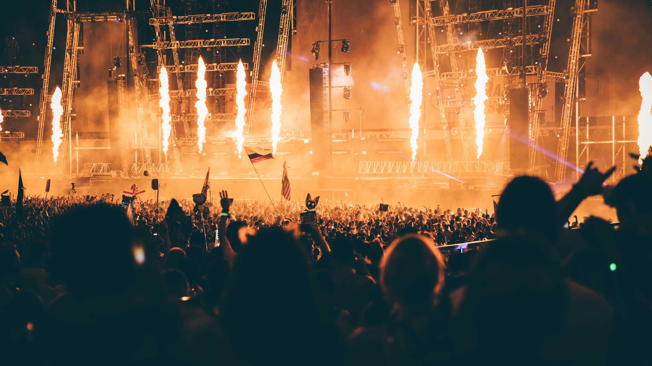 Large outdoor concert stage with fiery pyrotechnics shooting upward.
