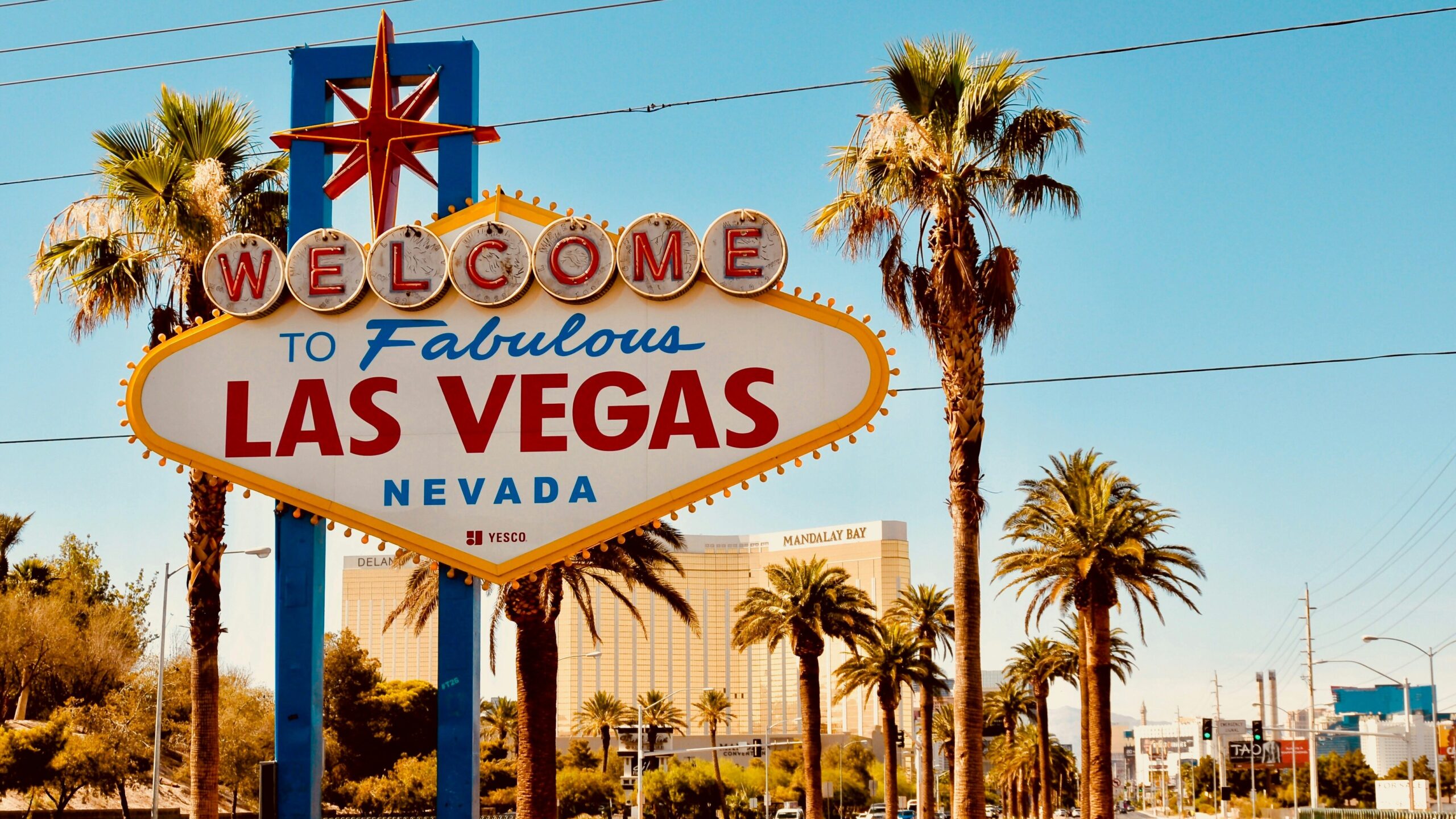 Welcome to Fabulous Las Vegas sign with palm trees and clear blue sky.