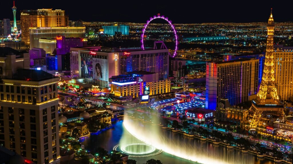 Bellagio fountain show at night with illuminated Las Vegas Strip hotels.
