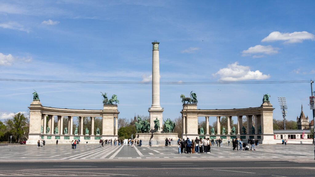 Wide view of Budapest's Heroes' Square showing the tall central column and equestrian statues.
