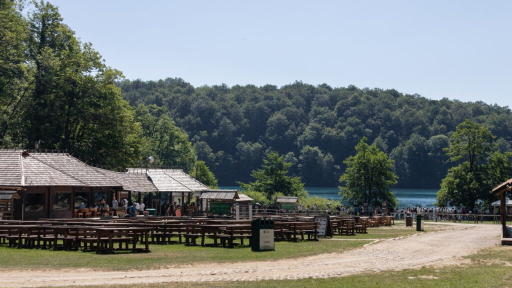 Plitvice Lakes | Krista the Explorer Lakeside park with a wooden pavilion, picnic tables, and people.