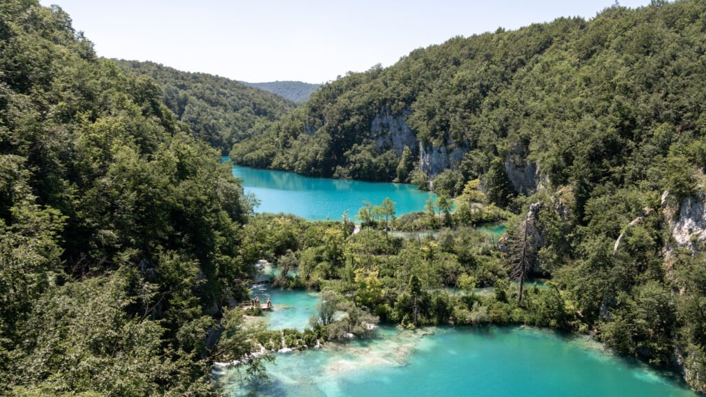 Plitvice Lakes | Krista the Explorer Turquoise lake nestled in a forested canyon with rocky cliffs.