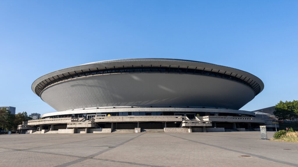 Large circular, disc-shaped building with a metallic textured exterior.