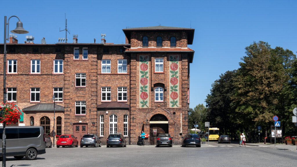Brick building with vertical rose murals on either side of a central entrance.