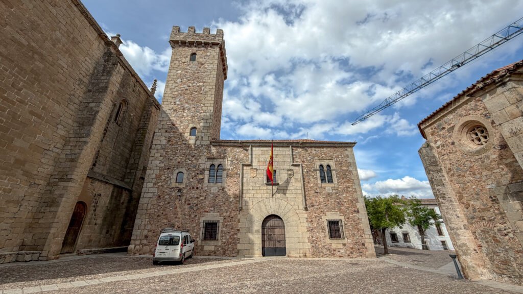 Palacio de las Cigüeñas Caceres | Krista the Explorer Stone fortress with a tall crenellated tower, arched windows, and a Spanish flag.