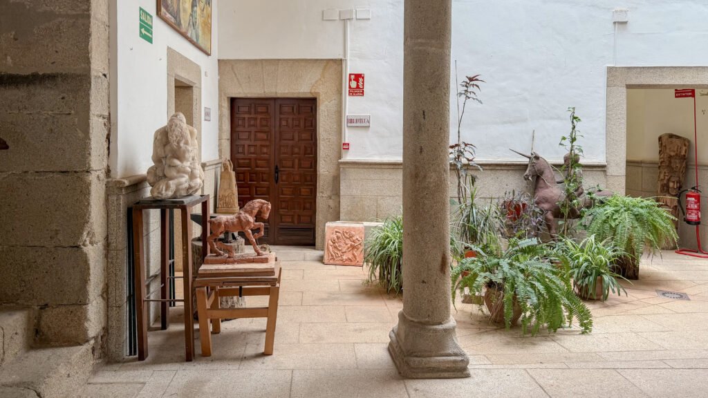 Courtyard Caceres | Krista the Explorer Indoor museum courtyard with statues, a large wooden door, and stone columns.