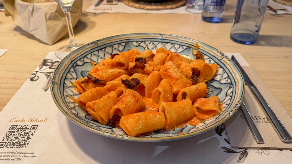 La Famiglia se sienta a la mesa Caceres | Krista the Explorer Rigatoni with deep red sauce and bacon pieces.