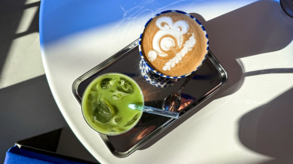Iced matcha and latte on sunny table in cafe.