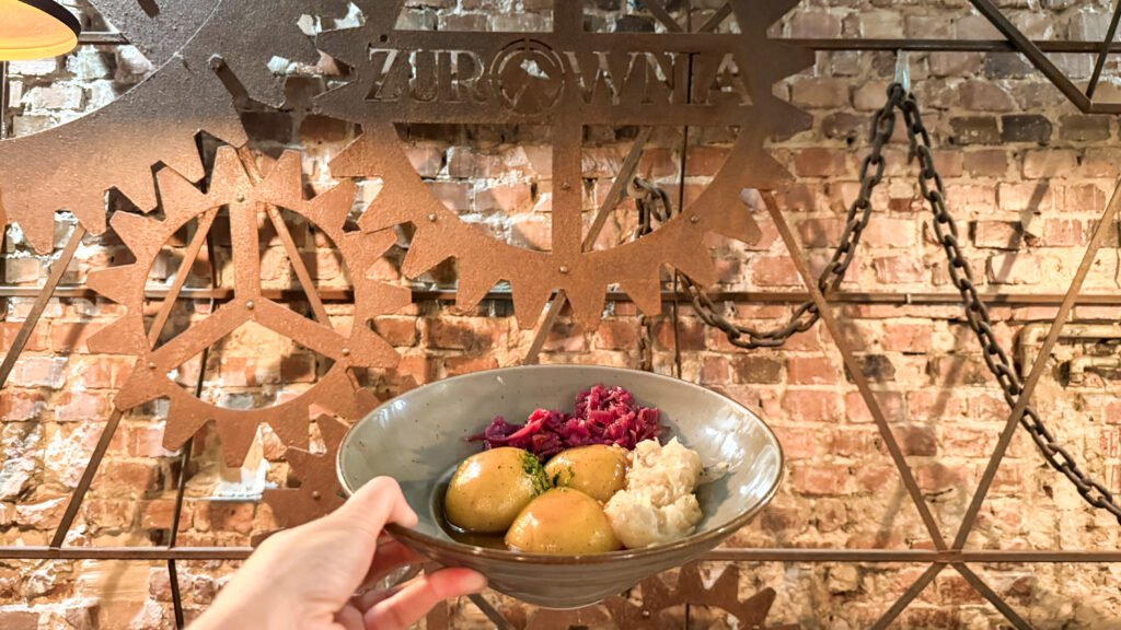 Hand holding a bowl with Silesian dumplings and beetroot.