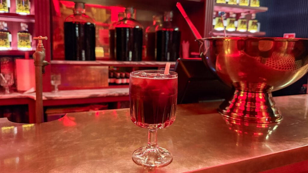 Tall stemmed glass with a dark red cherry liquor in modern bar.
