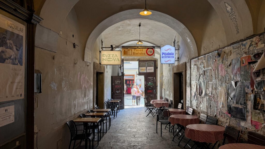 Bielak Passage Krakow | Krista the Explorer Arched pedestrian passage with café tables and hanging signs during a weekend in Krakow.