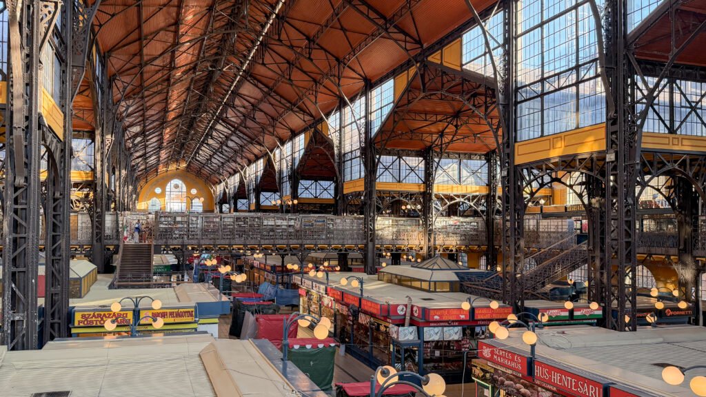 Interior of a large historic market hall with black wrought-iron framework.