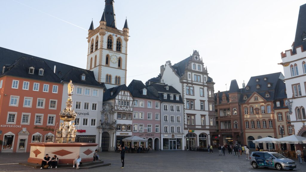 Trier Square | Krista the Explorer Colorful historic town square with a decorative fountain in the foreground at sunset.