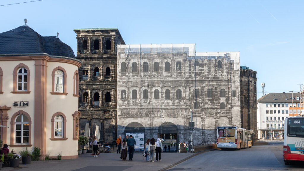 Porta Nigra Trier | Krista the Explorer Ancient city gate in black stone with scaffolding covering half of it.