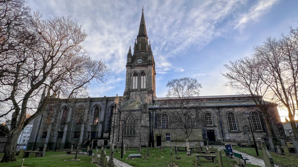 Kirk of St Nicholas Aberdeen | Krista the Explorer Gothic church with tall spire and clock, surrounded by leafless trees.