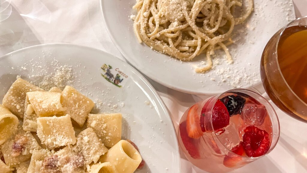 Checco Er Carettiere Rome | Krista the Explorer Plate of rigatoni pasta and spaghetti with grated cheese and cocktails.
