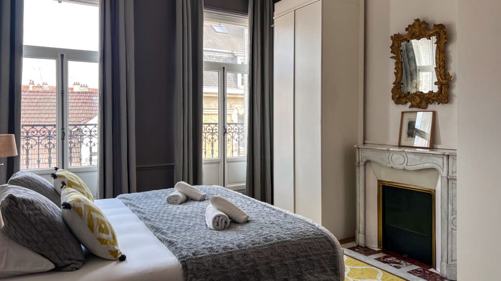 Reims Apartment | Krista the Explorer Hotel bedroom with double bed featuring grey throw and decorative pillows.