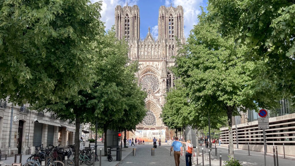 Front view of a historic Gothic cathedral framed by green trees.