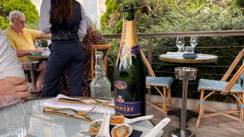 Pommery Reims | Krista the Explorer Champagne bottle centred on a glass table with small appetizer spoons.