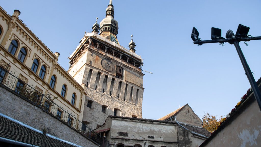 Historic clock tower with green-tiled roof and spires.