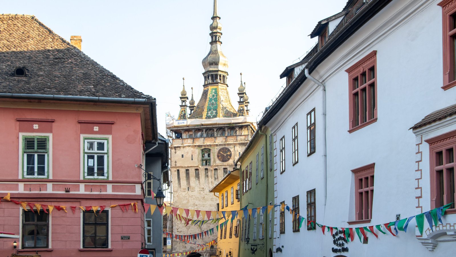 Sighisoara | Krista the Explorer | Krista the Explorer Colourful European street with pink, yellow, and white buildings.