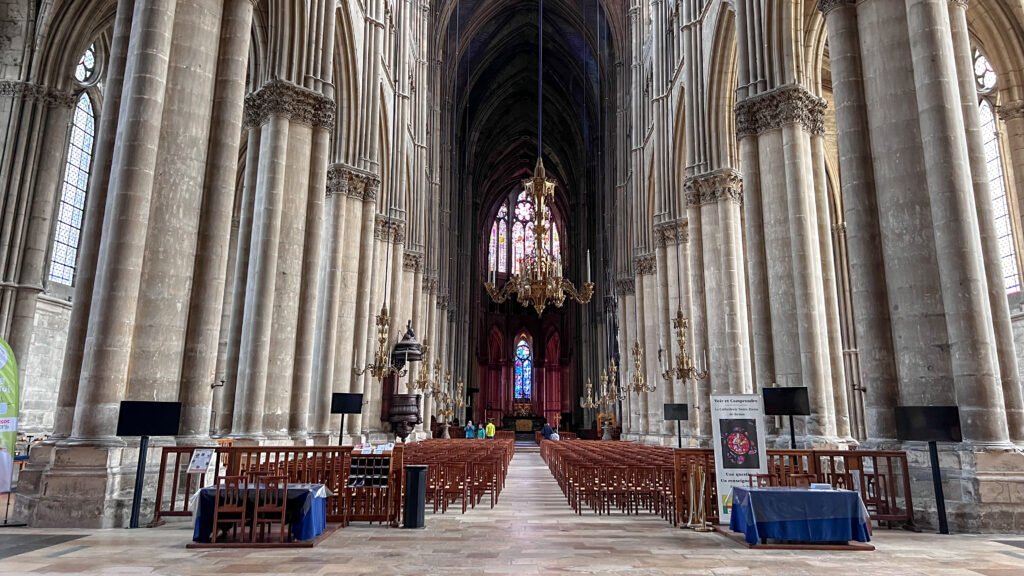 Cathédrale Notre-Dame de Reims | Krista the Explorer Interior of a Gothic cathedral with tall stone columns, arches, and a central chandelier.