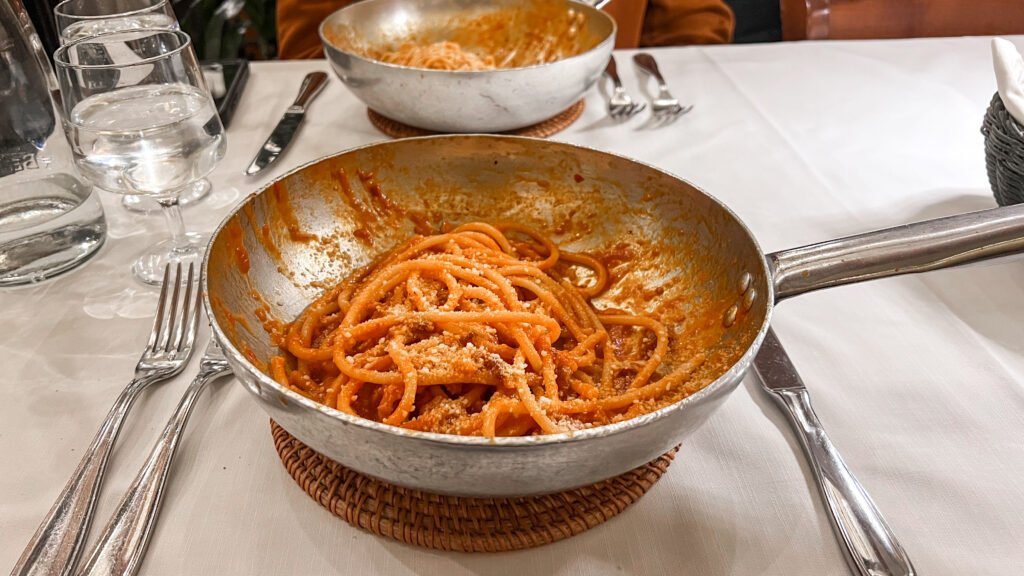Taverna Trilussa Rome | Krista the Explorer Pan of spaghetti with tomato sauce and grated cheese on a dining table.