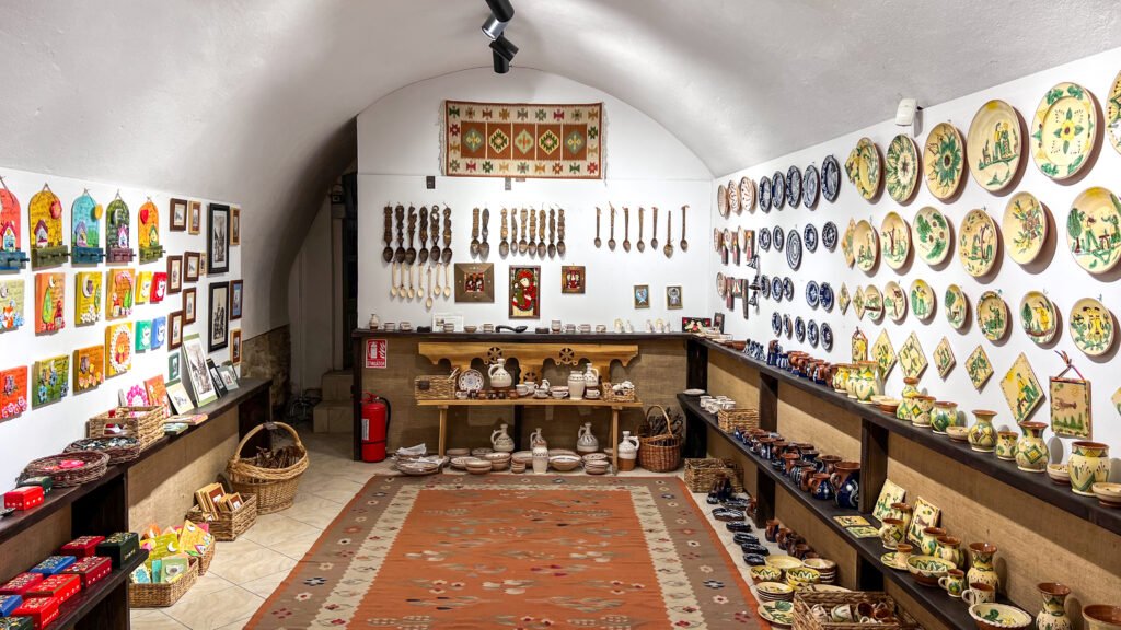 Interior of a pottery shop with clay mugs, bowls, and plates on shelves.