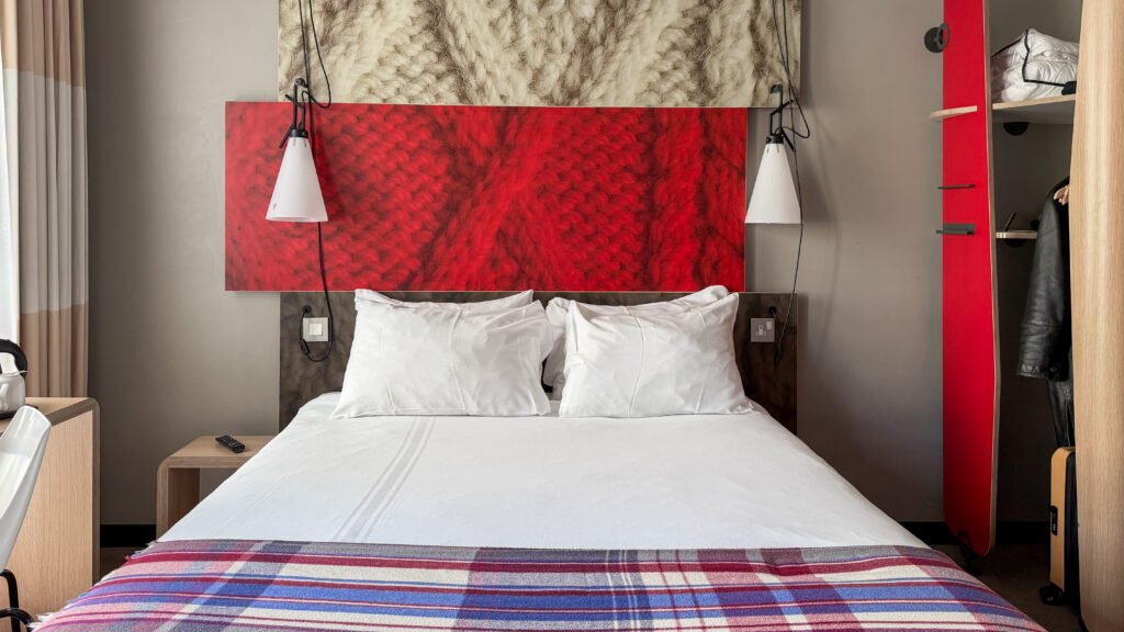 ibis Edinburgh Centre Royal Mile | Krista the Explorer Hotel bedroom with a large bed, white pillows, and a red textured headboard panel.