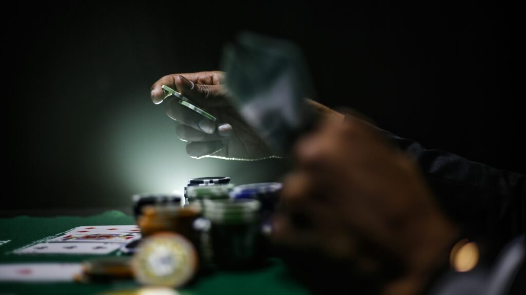 Close-up of a hand holding a playing card over a poker table.
