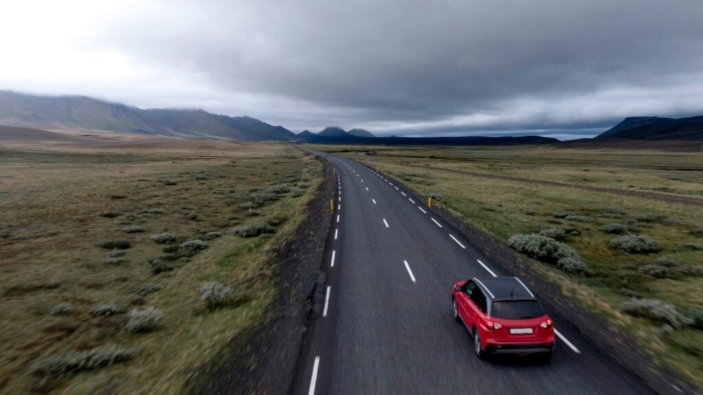 EconomyBookings | Krista the Explorer Two-lane highway through a flat grassy plain under a gray, stormy sky.